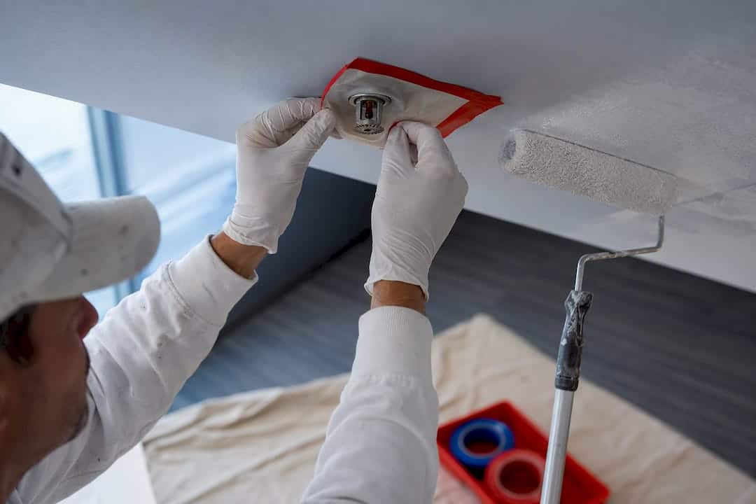 Painter masking sprinkler head before renovation